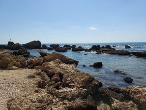 Una costa rocosa con agua azul cristalina y cielo despejado.