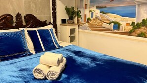 A bedroom with a bed, pillows, and a view of a coastal scene through an arched window. - Ahuzat Shaul Hotel Seaside (Hadera)
