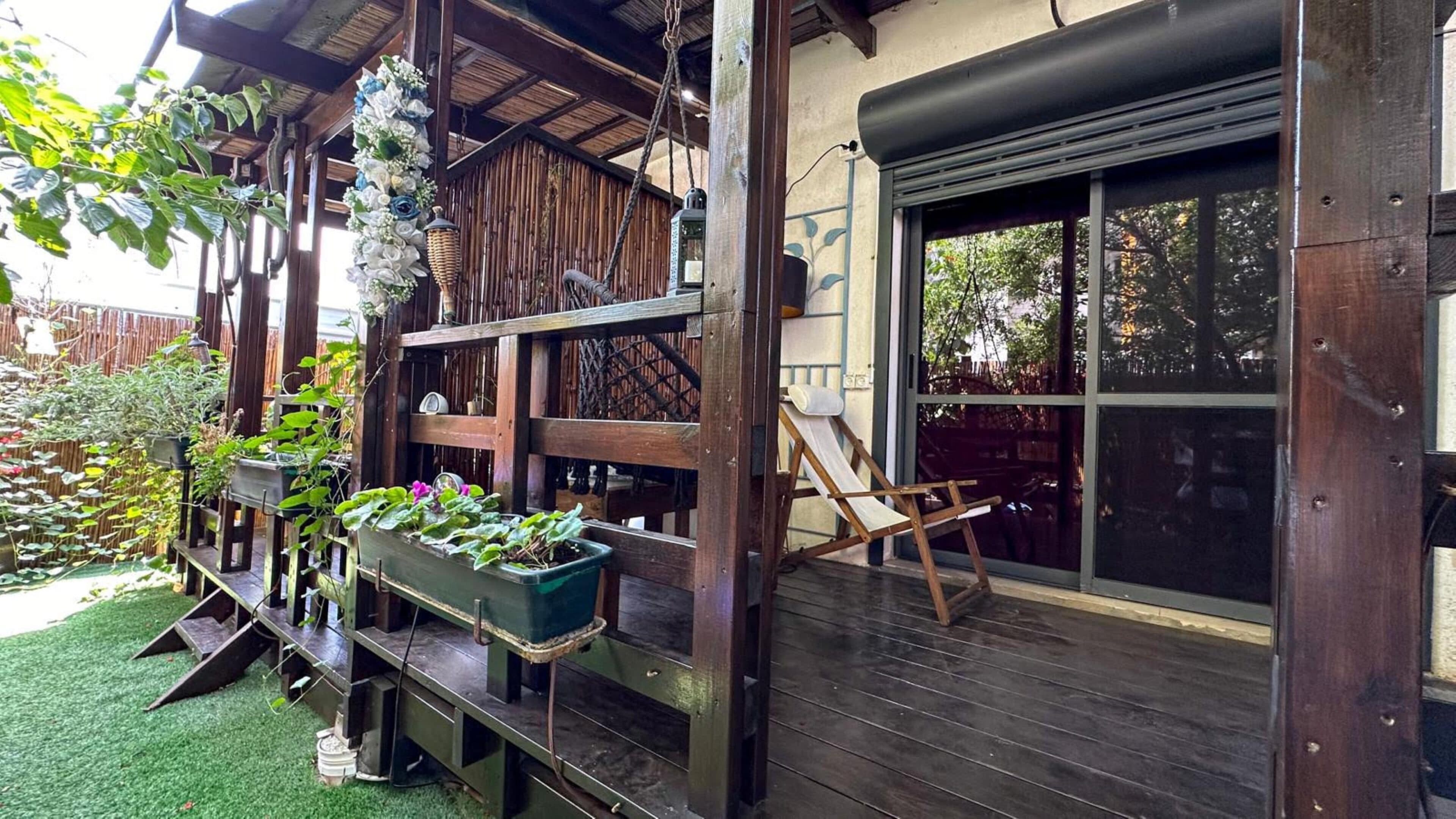 A wooden deck with a sliding glass door, a wooden fence, and various potted plants.
