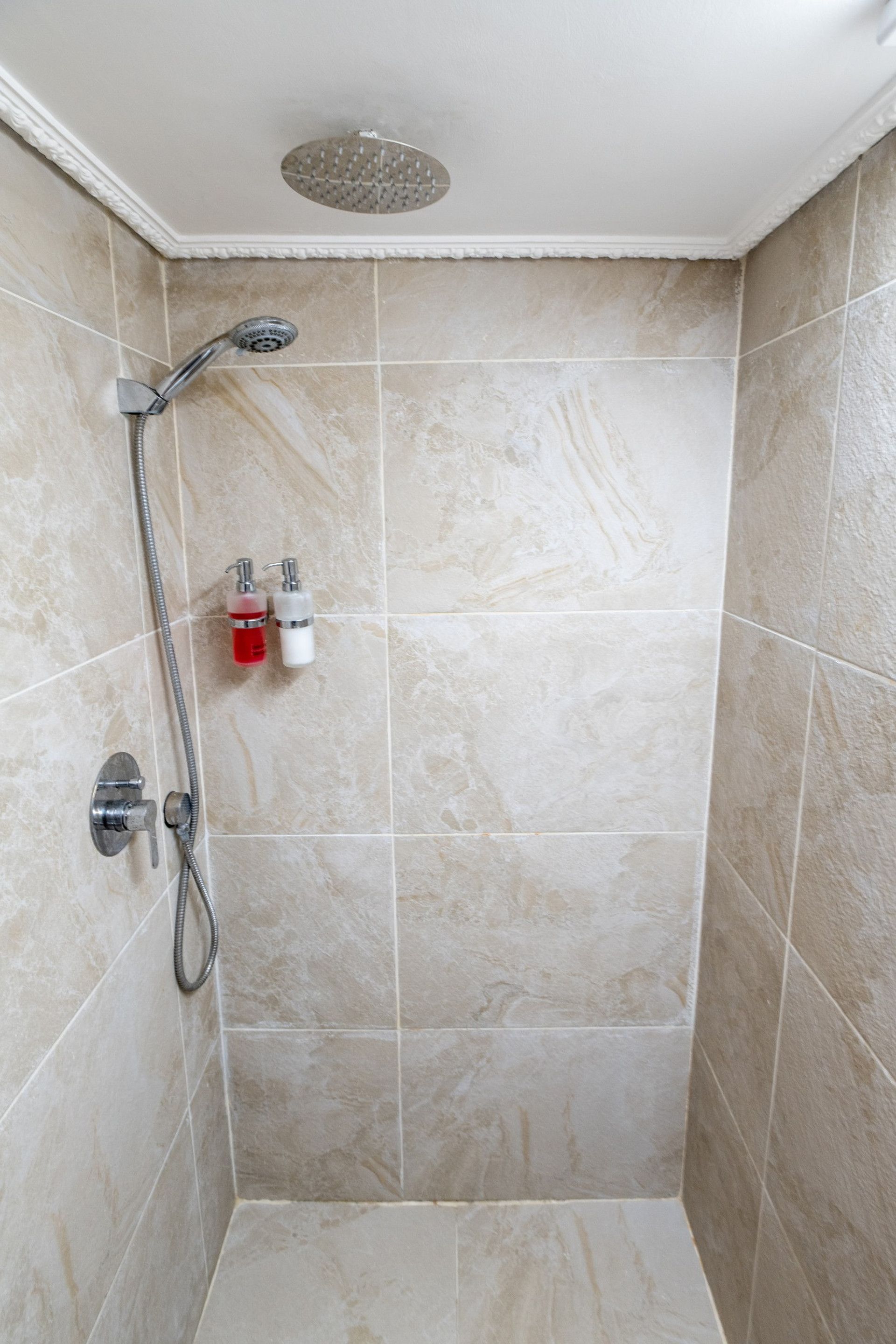 A shower with a handheld showerhead and a wall-mounted faucet.