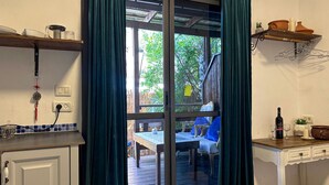 A kitchen with a dining area visible through a glass door, featuring a table and chairs, a wine bottle, and a small plant on the counter. - Ahuzat Shaul Hotel Seaside (Hadera)