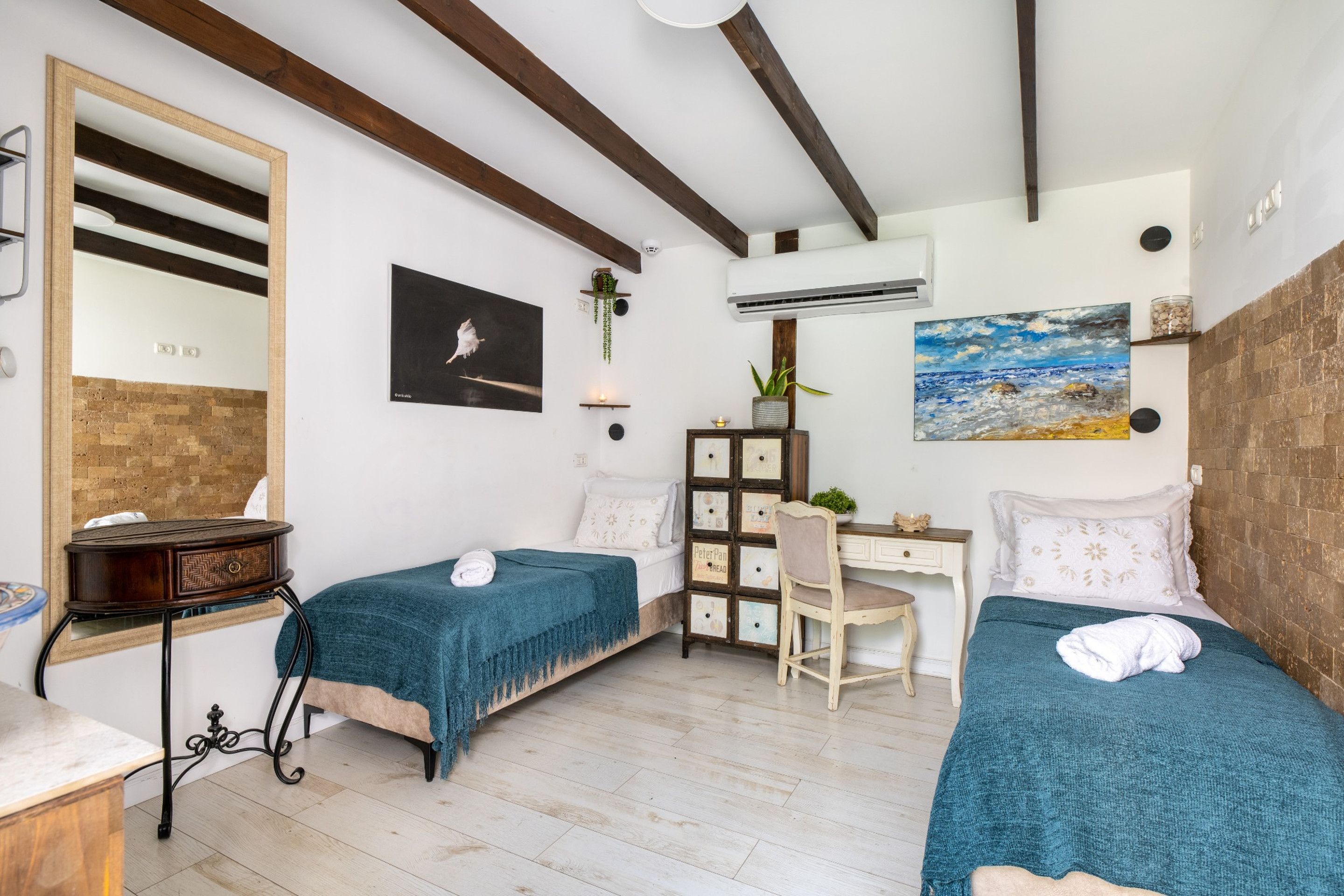 Een kamer met twee bedden, een bureau, een stoel, een spiegel en een schilderij aan de muur.