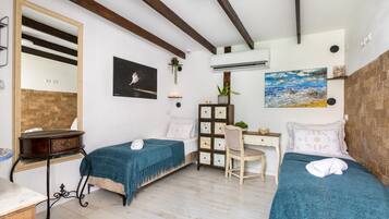 Een kamer met twee bedden, een bureau, een stoel, een spiegel en een schilderij aan de muur.