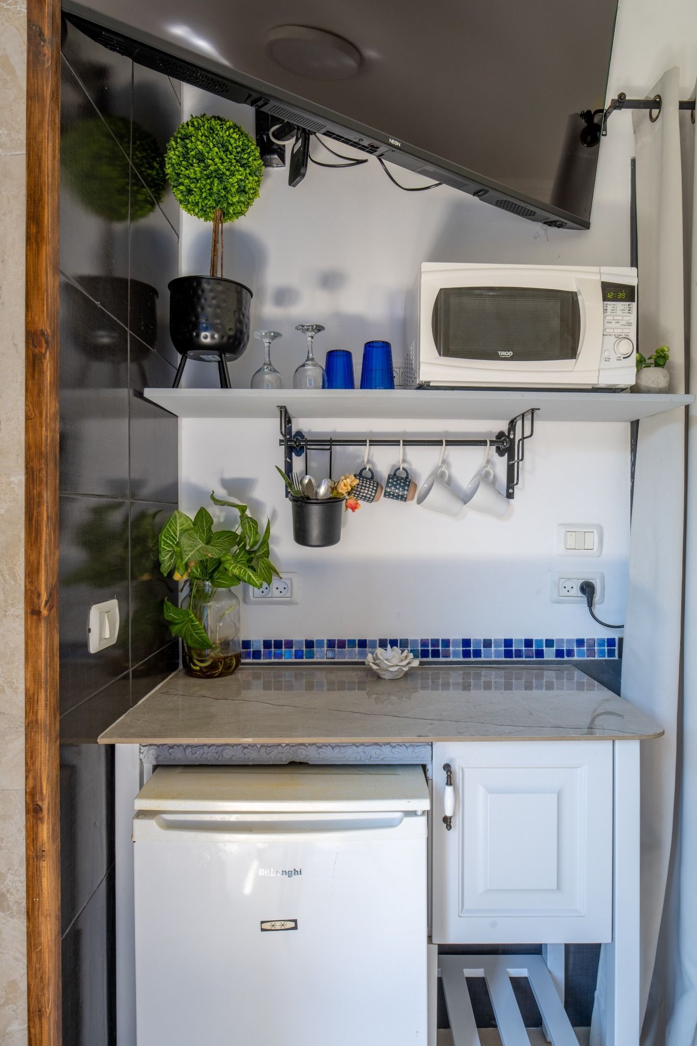 Una cocina funcional con un refrigerador blanco, un microondas y un lavamanos pequeño.