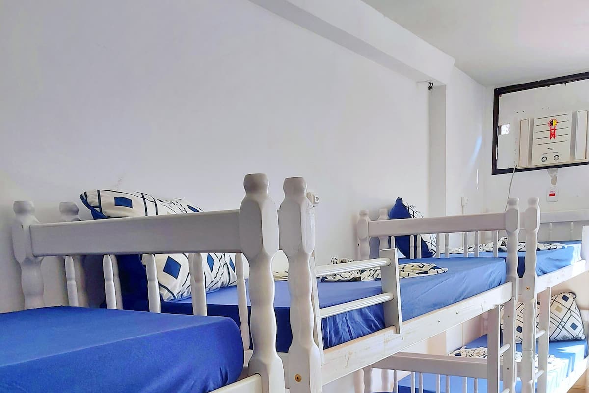 A room with bunk beds, each with a blue mattress and patterned pillows.