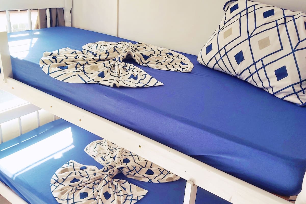 A bunk bed with a blue mattress and patterned pillows.