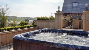 Un jacuzzi en una terraza con vistas a un edificio y al paisaje.