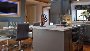 Una cocina moderna con una isla central, electrodomésticos integrados y un comedor con televisor.