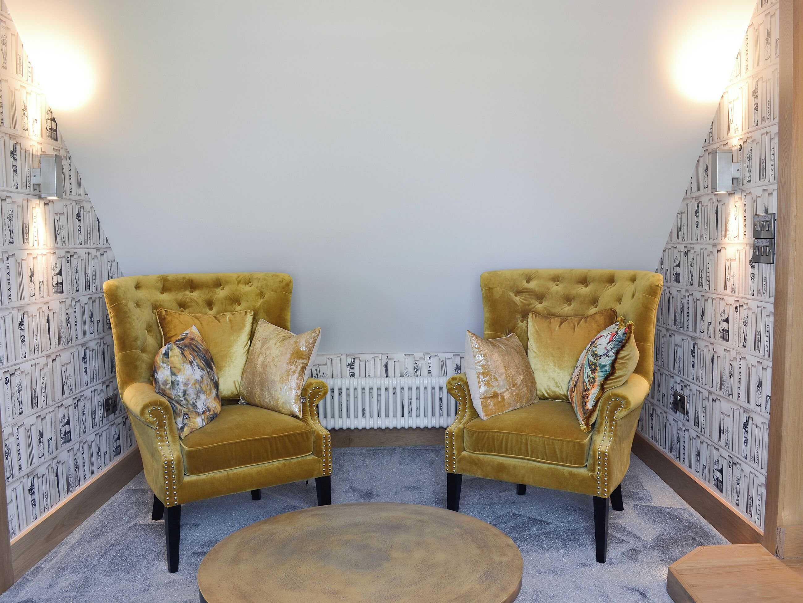A room with two armchairs, a round coffee table, and a radiator.