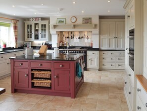 A kitchen with a central island, white cabinetry, a clock, and a 'HOME' sign.