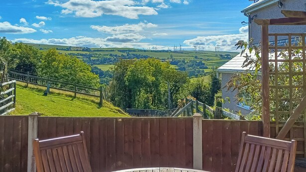 A wooden table and chairs with a view of a green landscape and wind turbines. - 2 bedroom accommodation in Prion, near Denbigh (Prion, near Denbigh)