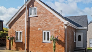 A two-story brick house with a gabled roof, two windows, and a door. - 2 bedroom accommodation in Prion, near Denbigh (Prion, near Denbigh)