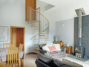 A living room with a spiral staircase, a fireplace, a sofa, and a dining area.