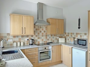 A kitchen with wooden cabinets, a stainless steel oven, a microwave, and a small refrigerator. - 2 bedroom accommodation in Prion, near Denbigh (Prion, near Denbigh)