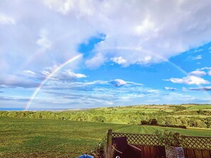 Un paysage rural avec un arc-en-ciel, des champs verdoyants et une clôture en bois.