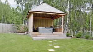 A wooden gazebo with a hot tub, surrounded by a well-maintained lawn and a wooden fence. - 5 bedroom accommodation in Aviemore (Aviemore)