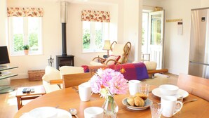 A dining area with a table set for breakfast, a sofa, a fireplace, and a television in the corner. - Quiet rural idyll near Salisbury. (Near Salisbury)