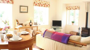 A cozy living room with a sofa, a dining table with chairs, a TV, and a fireplace. - Quiet rural idyll near Salisbury. (Near Salisbury)