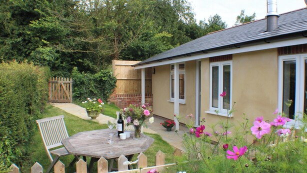 A house with a garden, a wooden fence, and a table with a bottle and glasses. - Quiet rural idyll near Salisbury. (Near Salisbury)