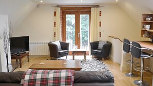 A cozy living room with a TV, two sofas, a coffee table, and a dining area with chairs. - 1 bedroom accommodation in Holt (Holt)