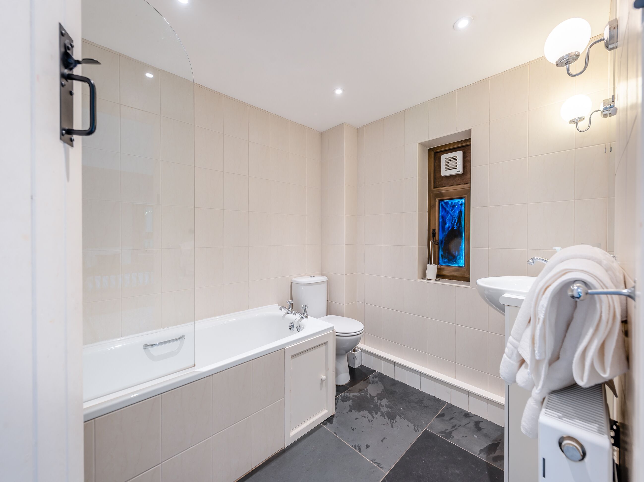 A bathroom with a bathtub, toilet, sink, and a towel rack.