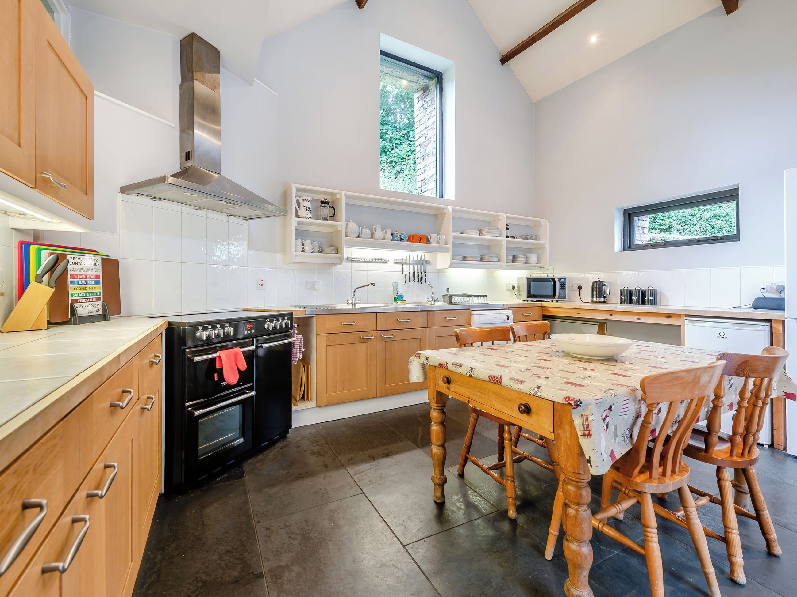 A modern kitchen with wooden cabinets, a black stove, and a dining table with chairs.