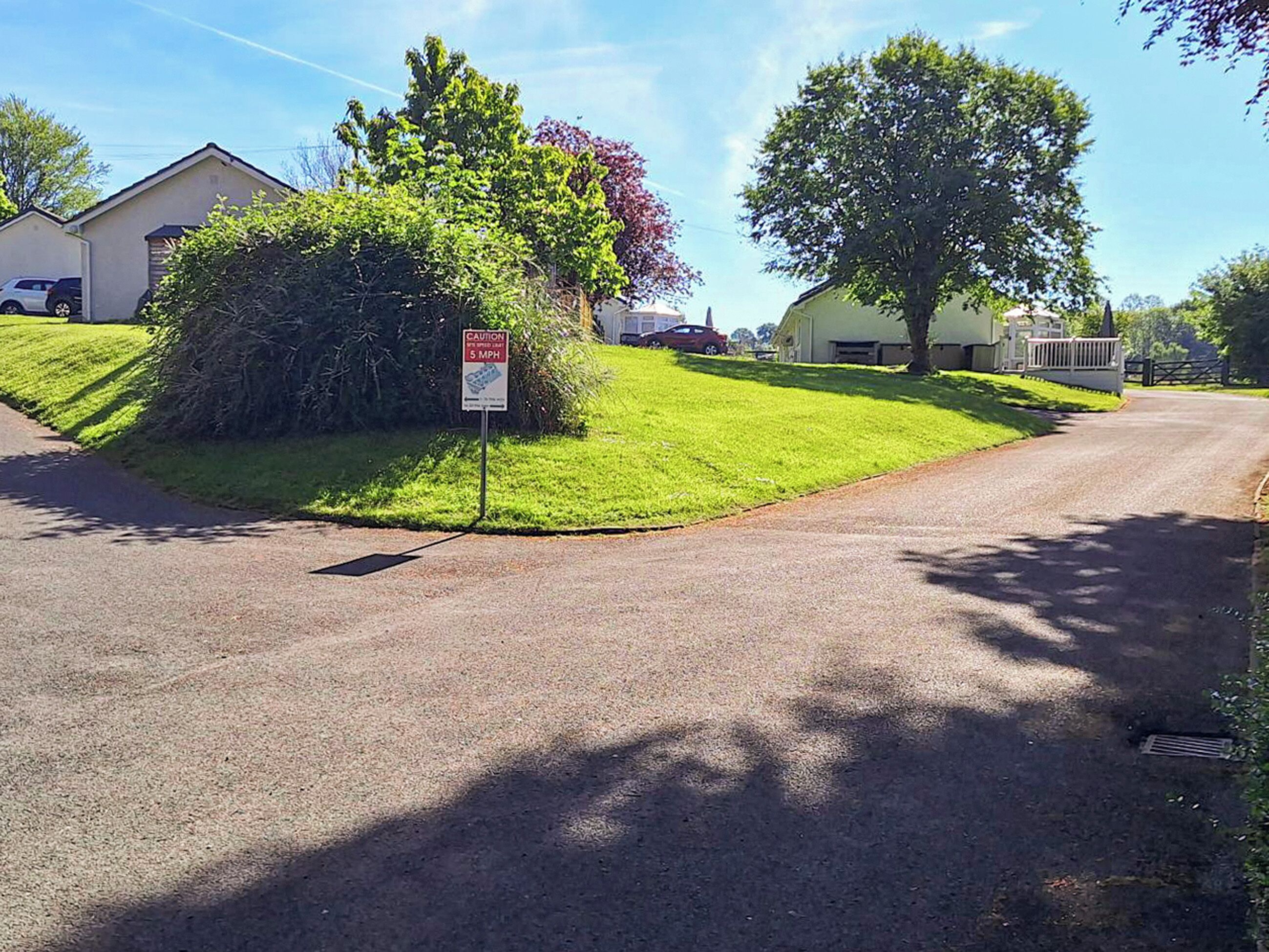 A residential street with a caution sign indicating a 5 mph speed limit.