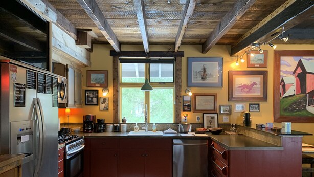 A kitchen with a large island, wooden ceiling beams, and various kitchen appliances. - Pristine Custom Cottage, Grand Piano, Massage Studio on Site (Leicester)