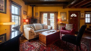 A cozy living room with a sofa, a red chair, a wooden coffee table, and a patterned rug. - Pristine Custom Cottage, Grand Piano, Massage Studio on Site (Leicester)