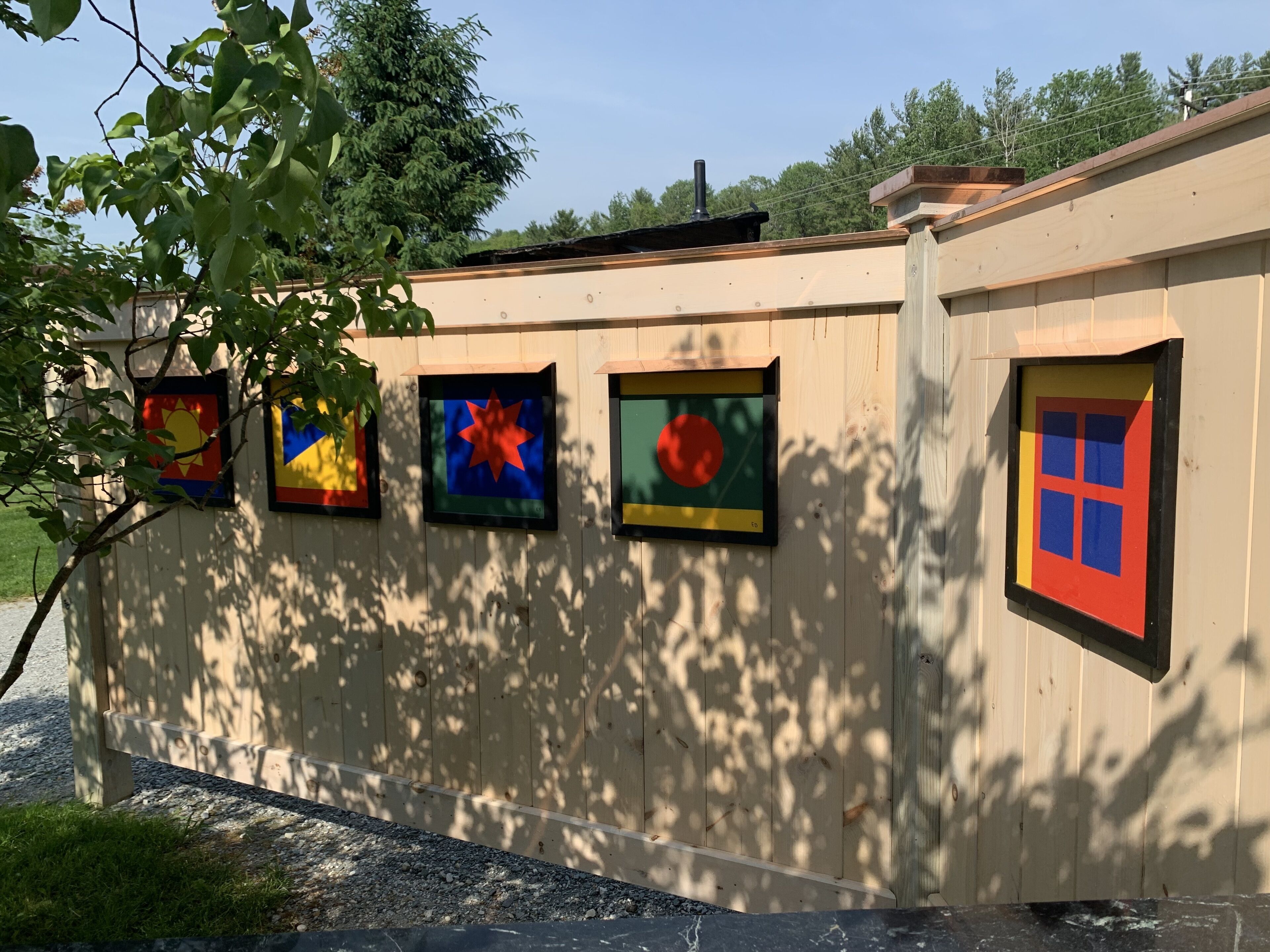 A building with a wooden exterior and a series of framed artworks on the side.