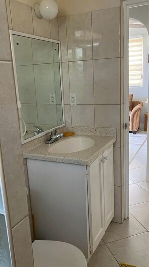 A bathroom with a white sink, mirror, and cabinet.