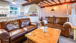 A cozy living area with a brown leather sofa, a wooden coffee table, and a dining table with chairs.