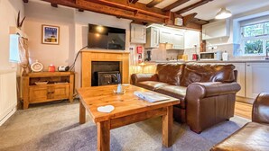 A cozy living room with a fireplace, leather sofa, wooden coffee table, and a television.