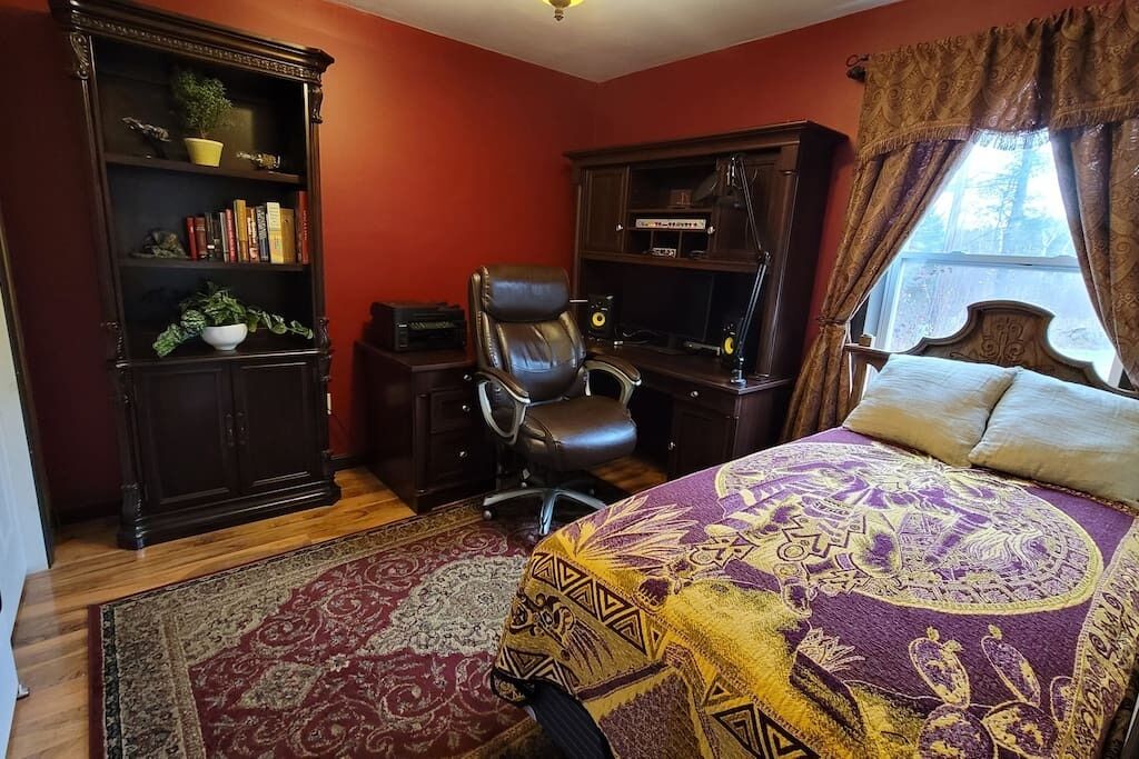 Une chambre à coucher avec un grand lit, un bureau, une chaise et des étagères.