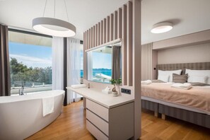 Un dormitorio moderno con una cama grande, una mesita de noche, un tocador empotrado y una bañera.