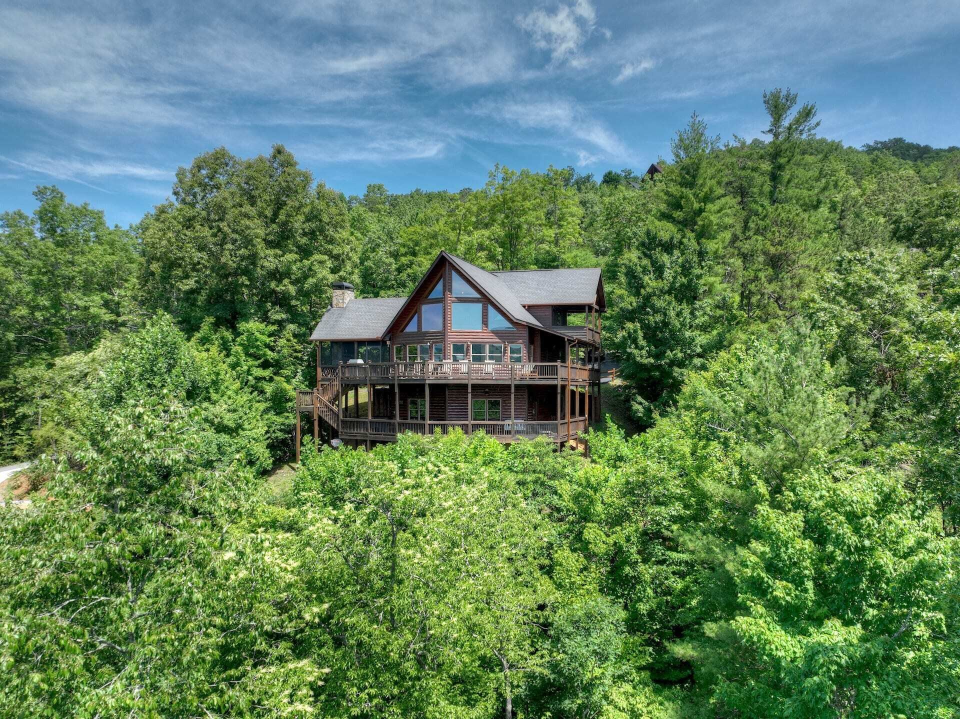 Une cabane en bois dotée d’un balcon, entourée d’une forêt dense.