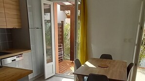 Kompakti keittiö, jossa on ruokailutila, kattotuuletin ja liukuovi, joka johtaa ulkoterasille.