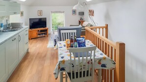 A bright kitchen with a TV, dining table, and chairs.