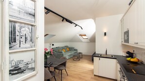 Eine moderne Küche mit Essbereich, einer Couch und einem Schlafzimmer im oberen Bereich mit Dachfenster.