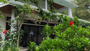 A two-story building with a covered porch and a garden area with various plants and flowers.