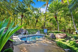 Une piscine naturelle entourée d’une végétation tropicale et un panneau indiquant les règles du centre de bien-être.