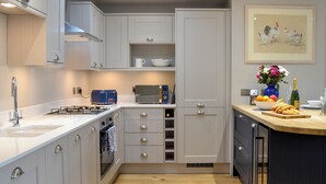 A modern kitchen with white cabinets, a gas stove, a microwave, and a sink. - Grange Loft - UK31594 (Dundee)