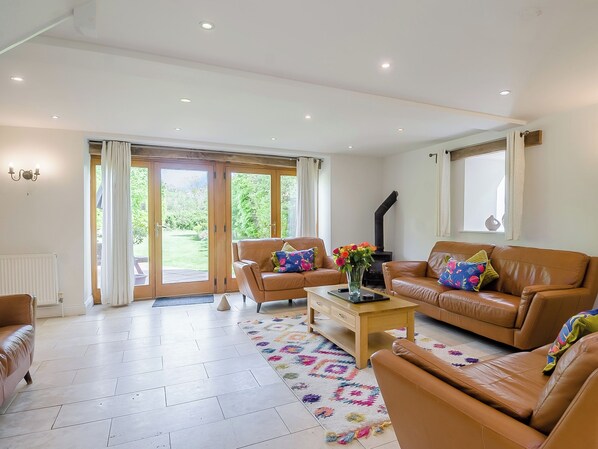 A spacious living room with two leather sofas, a coffee table, and a large window with a view of a garden.