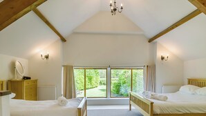 Una habitación con dos camas, techo de madera, un ventanal grande y un candelabro.