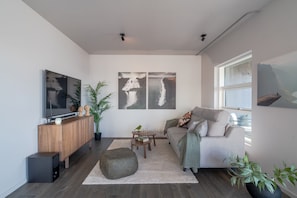 Relax in this stylish living room with a large flat-screen TV, comfortable sofa, and potted plants.