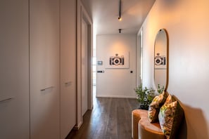 Experience the serene ambiance of this stylish hallway, featuring a large mirror, framed photography, and a cozy chair.