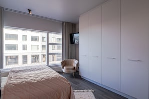 Relax in a spacious room with a large bed, city view, and comfortable seating area.