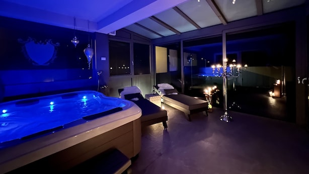 A modern spa area with a hot tub, lounge chairs, and a large window overlooking the city at night. - Garden/whirlpool/combination sauna large kitchen, rain shower. Very modern (Habscheid)