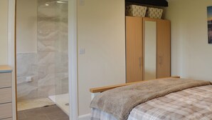 A bedroom with a bed, a wardrobe, a shower area, and a small desk. - 1 bedroom accommodation in Alkham, near Dover (Alkham, near Dover)