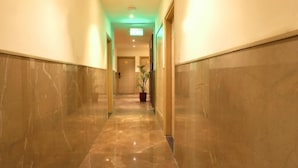 A hallway with marble floors and walls, leading to a door at the end. - Sagar Residency (Amritsar)
